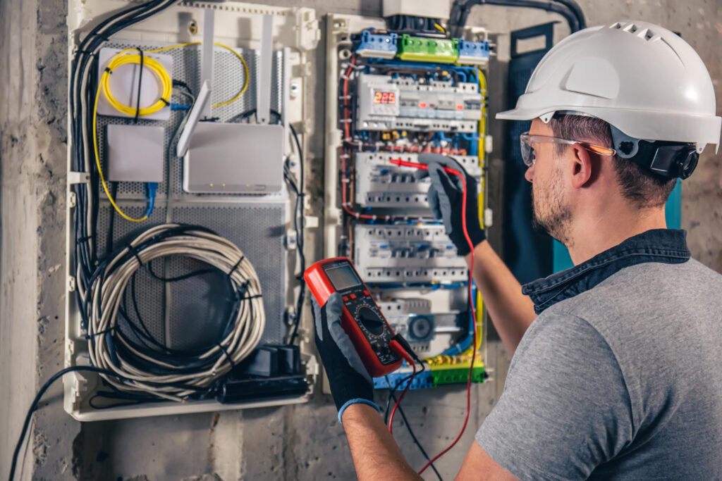 Electrician testing a fuse board with a multimeter, showcasing electrical safety and compliance services related to PAT testing and domestic installations.