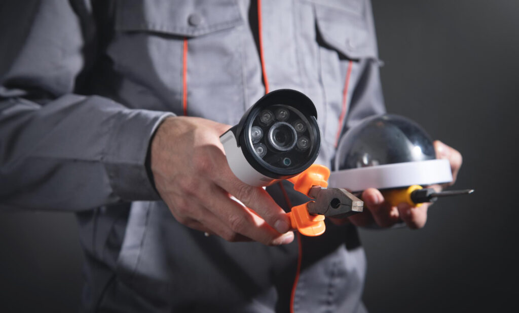 Electrician holding security camera and tools, illustrating electrical installation and safety services.